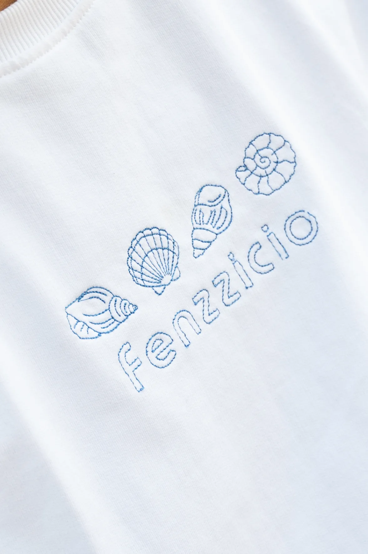 Close-up of the blue seashell and Fenzzicio wordmark embroidery