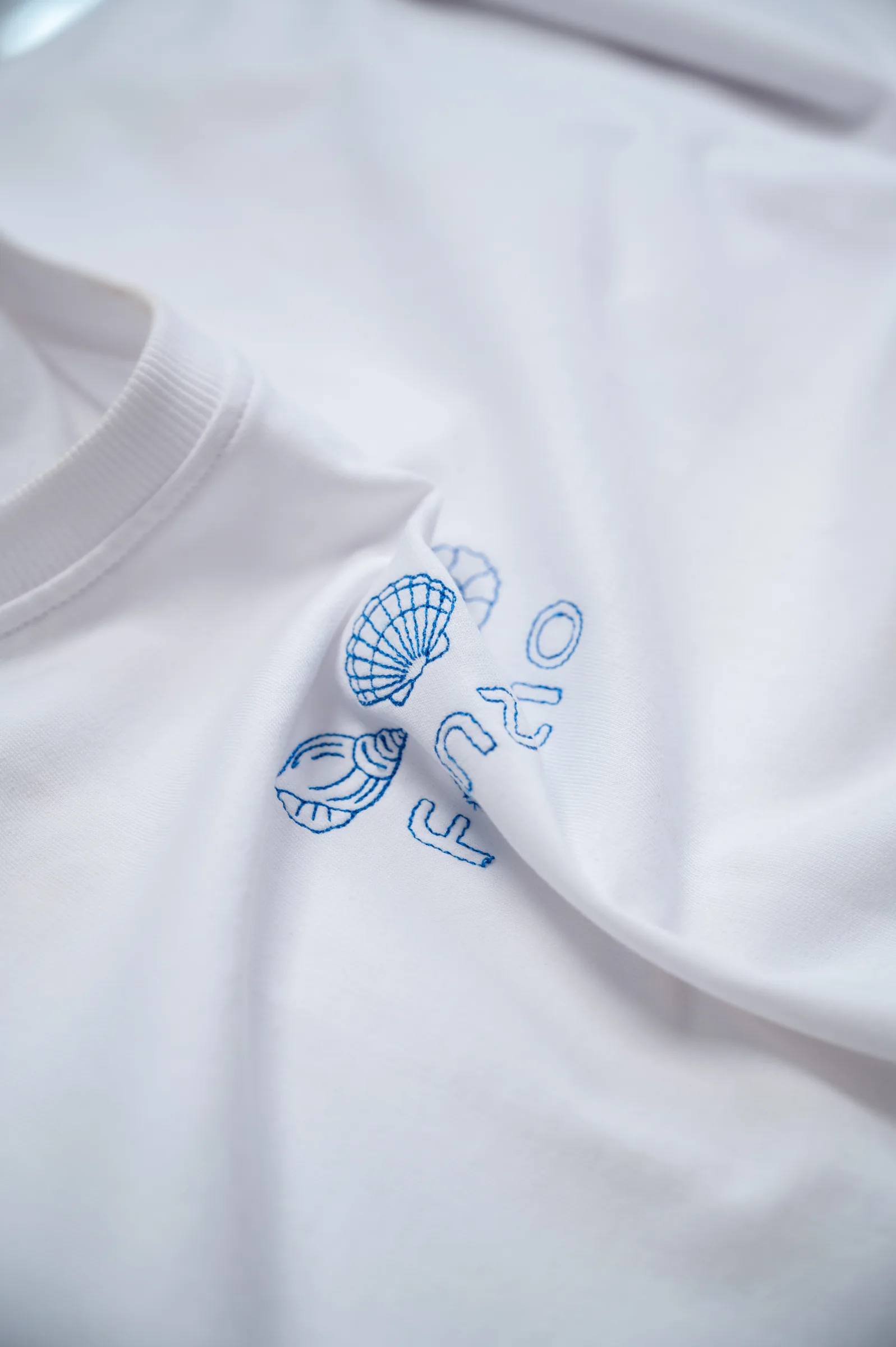 Angled close-up of the seashell embroidery on the chest
